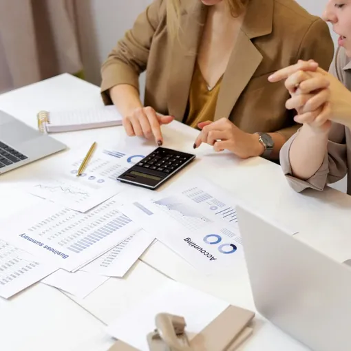 Analytics and Reporting Collaboration – Stellar Digital Media Team reviewing financial data and analytics reports with laptops and calculator, representing Stellar Digital Media analytics and reporting services.