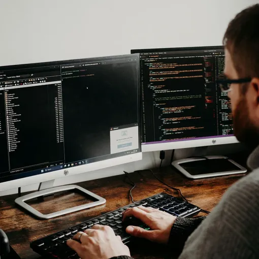 Web developer working on dual monitors with code and file management, representing Stellar Digital Media’s custom web development and support services.