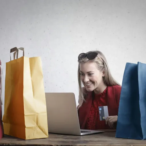 Magento Development and Support for Ecommerce Growth | Stellar Digital Media Woman shopping online with credit card and laptop surrounded by bags, representing ecommerce success with Magento