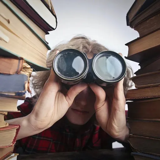 Person using binoculars between stacks of books symbolising research and analysis for paid ads services