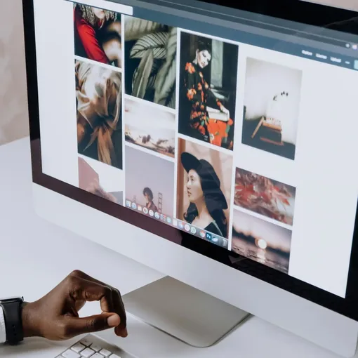 Designer working on a desktop computer with a gallery of creative website layouts, representing Webflow web design.