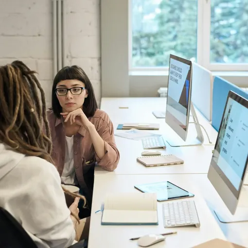 Team collaborating in an office with computers and notebooks, representing Webflow website design and support.