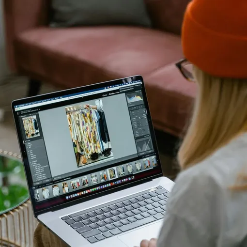 Designer working on a laptop editing clothing photos, symbolising creative Wix website design and professional support.