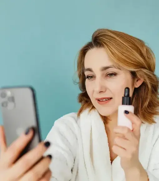 Woman creating social media content on smartphone while showcasing a skincare product, representing influencer marketing and brand promotion | Social Media Marketing Agency NZ
